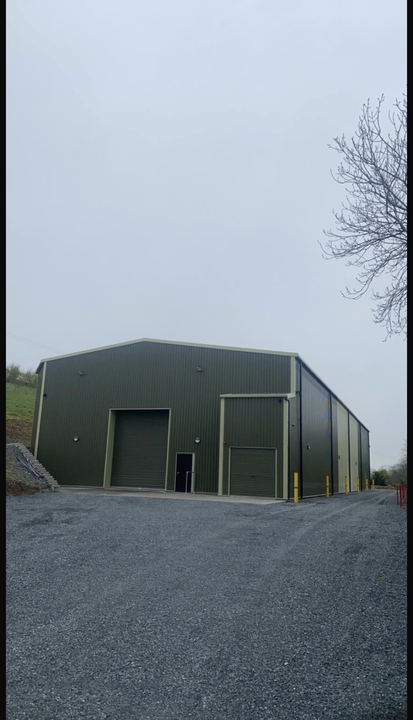 Completed green steel cladded agricultural building with roller doors