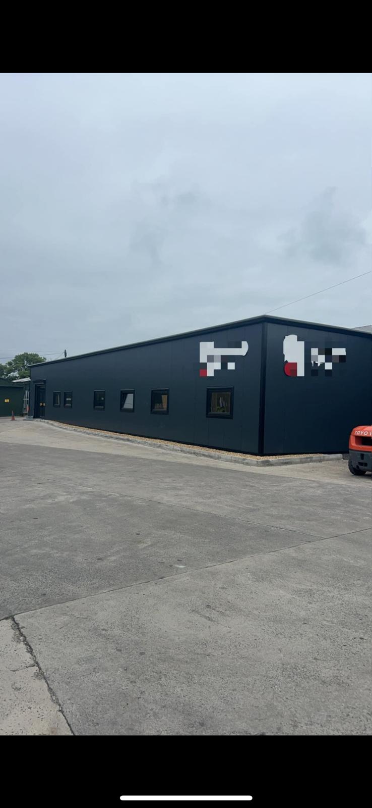 Dark steel cladded industrial building with forklift on site